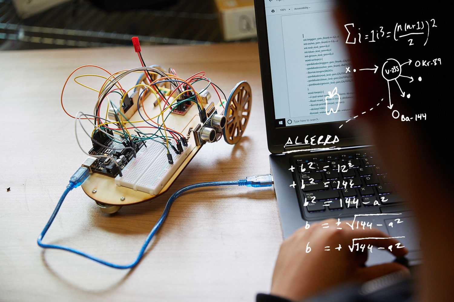 a small wheeled robot sitting next to a laptop computer